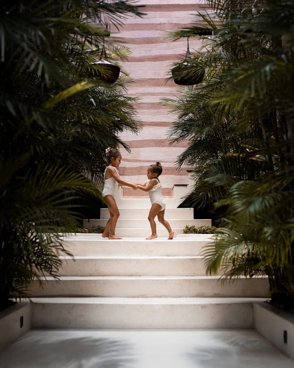 Editorial lifestyle: two girls holding hands on tropical villa steps